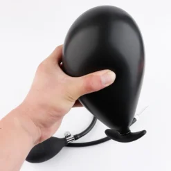 Mão segurando plug anal inflável preto inflado em forma de balão