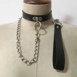Coleira BDSM preta com argola e guia de corrente pendurada, vestida em um manequim