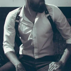 Homem de camisa social usando harness masculino preto estilo suspensório