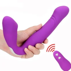 Strapless strapon vibrador roxo segurado na mão com o controle remoto ao lado