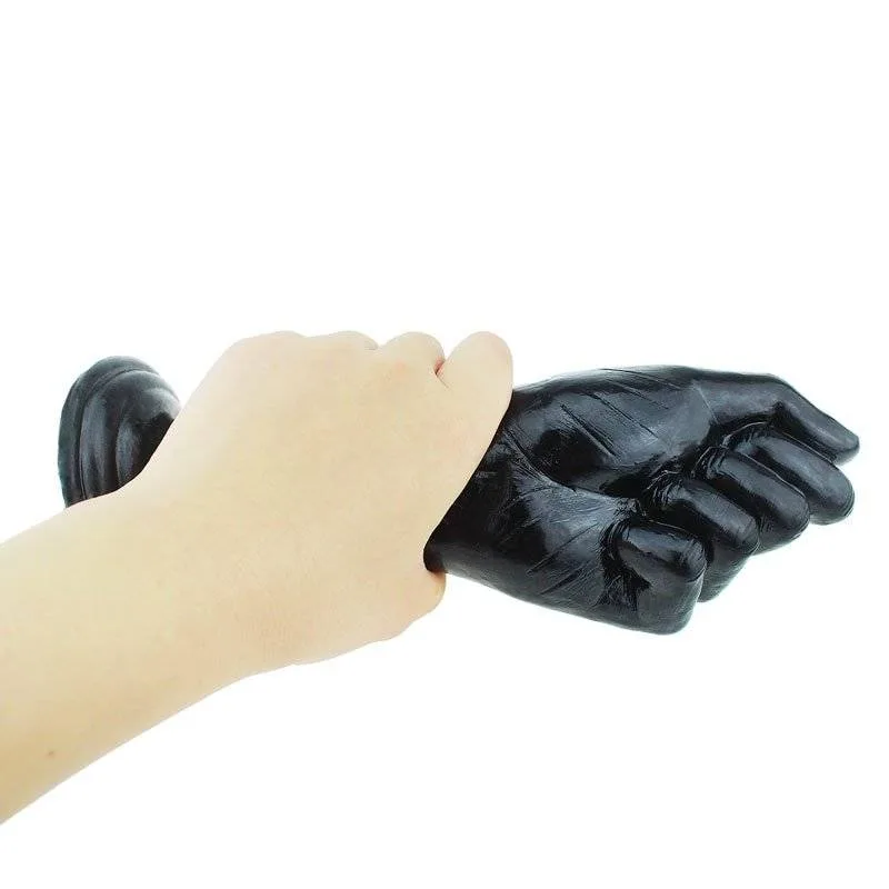 Dildo punho preto de fisting ao lado de um braço para mostrar o tamanho real