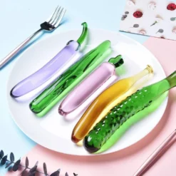 Cinco dildos de vidro de frutas e vegetais num prato