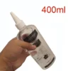 Mão segurando o frasco transparente de 400 ml de lubrificante solúvel em água com bico injetor branco