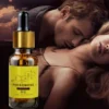 Frasco âmbar de perfume feromônio em óleo com rótulo amarelo, tampa dourada e conta-gotas sobre fundo de casal