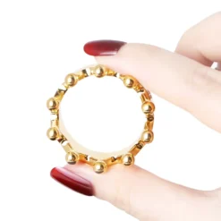 Cock ring Golden Crown dourado segurado entre os dedos