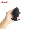 Mão segurando o plug anal de silicone preto em formato de pêssego, tamanho XL