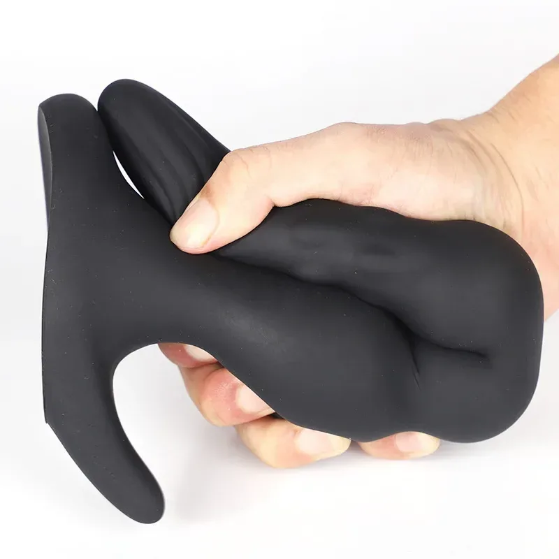 Plug anal preto gigante segurado com a mão fechada mostrando a grossura do corpo