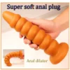 Plug anal de silicone dourado com segmentos arredondados e ventosa segurado na mão