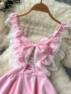 Vestido rosa com laço grande no peito e decote em V com renda