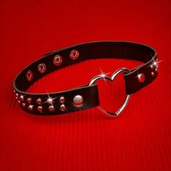 Choker de couro preto com coração prateado e tachas sobre fundo vermelho