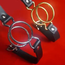 Ring gag de anel duplo prata e dourado sobre fundo vermelho