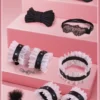 Kit de restrições BDSM de 10 peças com babado de renda branca, aberto sobre fundo rosa