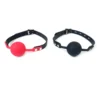 Mordaça ball gag com bola de silicone de 5 cm nas versões preta e vermelha lado a lado