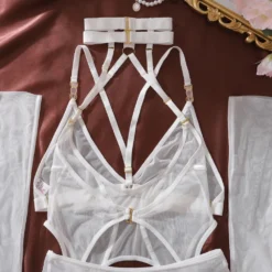 As cinco peças do conjunto Ellolace: choker, body, calcinha, luvas e meias, dispostas juntas