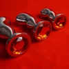 Três plugs anais de metal curvos com joia âmbar na base