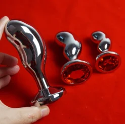 Mão segurando o plug anal de metal curvo grande