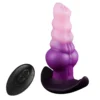 Plug anal monster vibratório de silicone em degradê rosa e roxo, ao lado do controle remoto sem fio