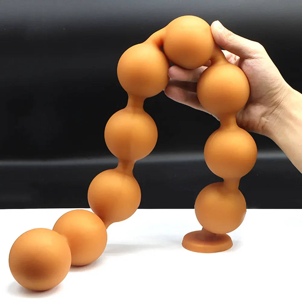 Plug anal de nove bolas dourado sendo dobrado pela mão, mostrando a flexibilidade