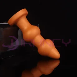 Plug anal gigante em beads dourado visto de lado com a base de ventosa