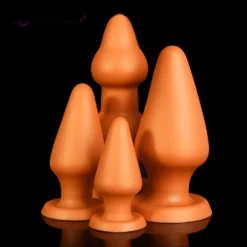 Três plugs anais gigantes em cone dourado nos tamanhos pequeno, médio e grande lado a lado