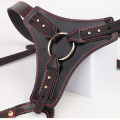 Detalhe do O-ring metálico removível e dos rebites dourados da cinta strapon