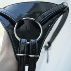 Detalhe do O-ring de metal e das fivelas da cinta peniana de verniz